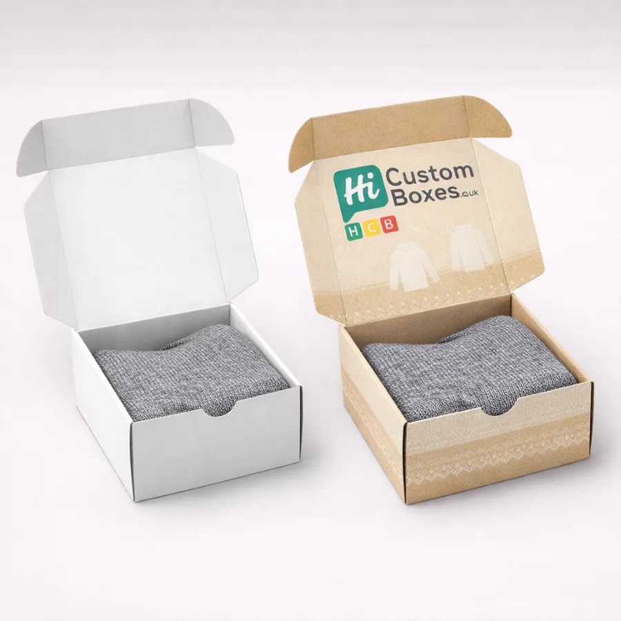 Two open mailer boxes- one white and one branded kraft- containing neatly folded grey knitwear-